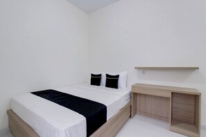A single bed with a white mattress and black bedding, a bedside table, and a wooden nightstand.