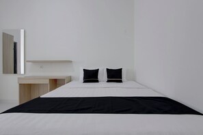Habitación de hotel minimalista con una cama individual, una mesita de noche y un espejo.