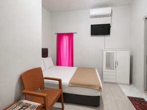 Ein Schlafzimmer mit einem Bett, einem Sessel, einem Kleiderschrank und einem Fernseher.