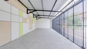 Un espacio interior amplio con suelo de baldosas y techo con estructura metálica.