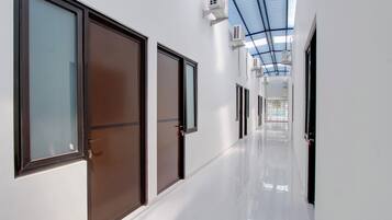 Un passadís amb portes, un sòl reflectant i ventiladors al sostre.