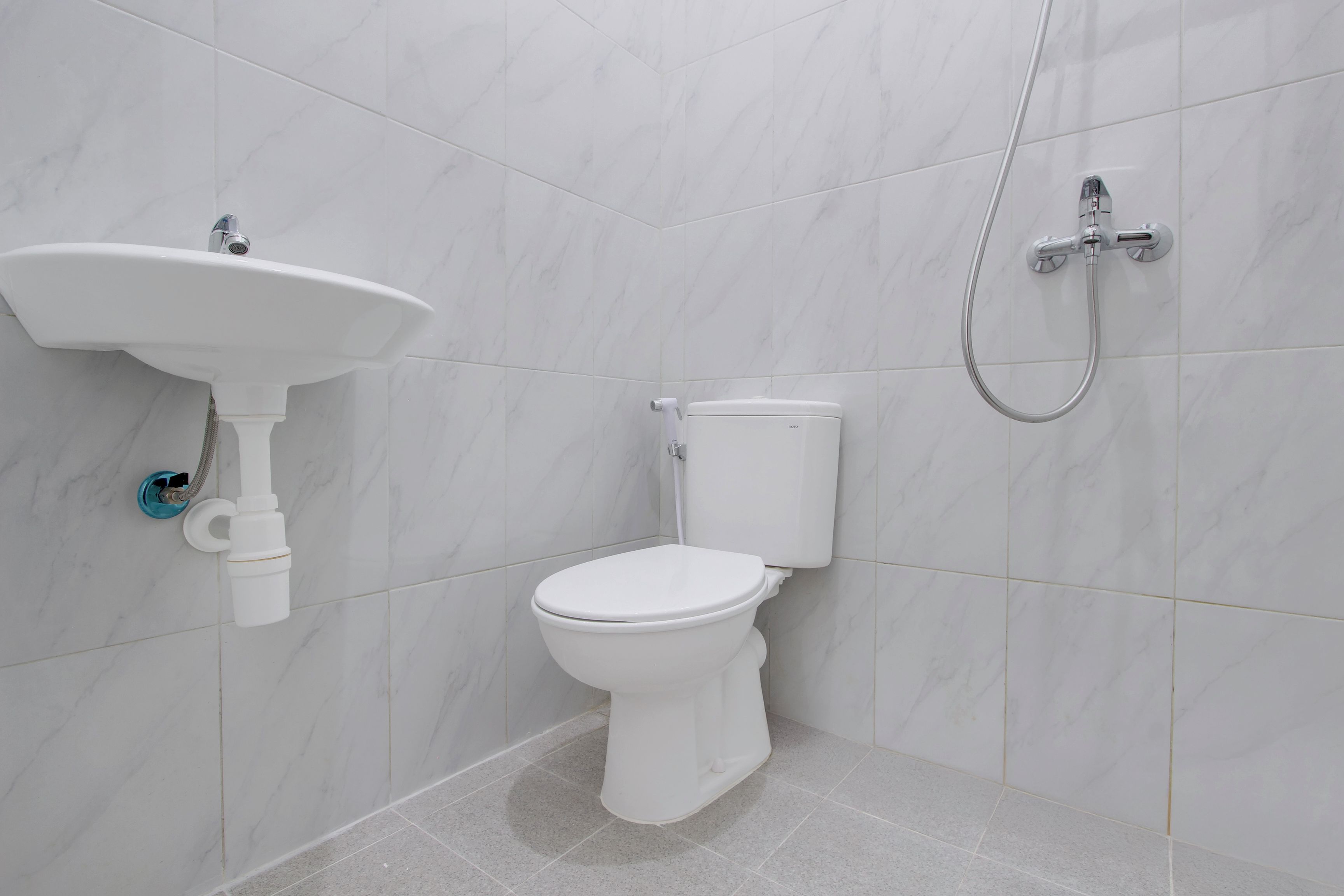 Un baño con inodoro blanco, lavabo y ducha.