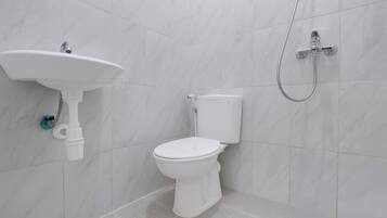 Un baño con inodoro blanco, lavabo y ducha.