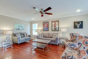 Ein Wohnzimmer mit zwei Sofas, einem Couchtisch, einem Deckenventilator und Wandbildern.