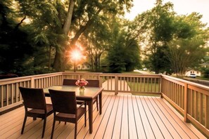A wooden deck with a table and chairs, surrounded by trees and a view of a house. - Stylish Getaway Prime Location Near Downtown (Nashville)