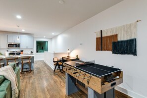 Una cocina moderna con área de comedor, una mesa de fútbol y un tapiz colgado en la pared.