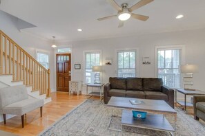 A spacious living room with hardwood floors, a brown sofa, a coffee table, and a staircase. - 3BR + Gated Parking | Sleeps 8 /Mins to Broadway (Nashville)