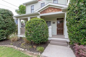 A two-story house with a front porch, a wooden shingle roof, and a well-maintained garden. - Two Modern Home Retreat Near Downtown! Sleeps 18! (Nashville)