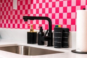 Un lavabo de cocina con un grifo moderno, un dispensador de jabón y un perchero con una toalla blanca.