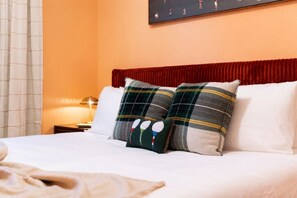 A hotel room with a bed, two pillows, a nightstand, a lamp, and a painting on the wall. - Rocky Top + Boho Nashville Duo | Sleeps 12 (Nashville)