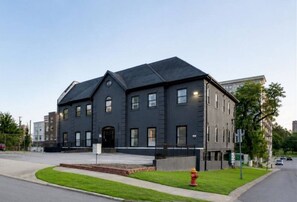 A modern two-story building with a flat roof, a front entrance, and a fire hydrant on the sidewalk. - Rocky Top + Boho Nashville Duo | Sleeps 12 (Nashville)