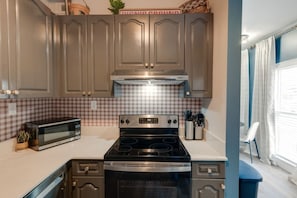 A kitchen with a microwave, stove, and checkered backsplash. - Chic+Cozy Nashville Duo | Sabrina & Cabin|Sleeps 8 (Nashville)