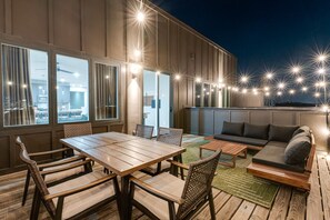 An outdoor patio with a wooden table and chairs, a sofa, and string lights. - Nashville Stay Near Downtown | 3BR on Fern Ave (Nashville)