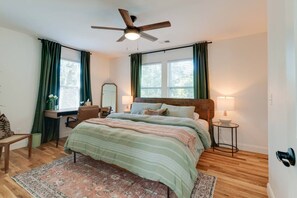 A bedroom with a bed, bedside tables, a desk, a chair, a ceiling fan, and a window with curtains. - Nashville Getaway | Spacious 3BR + 3BA Home (Nashville)