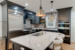 A modern kitchen with a large island, stainless steel appliances, and pendant lighting. - Nashville Getaway | Spacious 3BR + 3BA Home (Nashville)