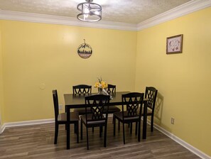 A dining room with a table and chairs, a decorative wall piece, and a ceiling light fixture. - 3-bedroom townhome in lovely Lithonia with cool AC (Lithonia)