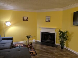 A living room with a fireplace, yellow walls, and a blue sofa. - 3-bedroom townhome in lovely Lithonia with cool AC (Lithonia)