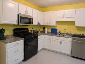 A kitchen with white cabinets, a black stove, a microwave, and a dishwasher. - 3-bedroom townhome in lovely Lithonia with cool AC (Lithonia)