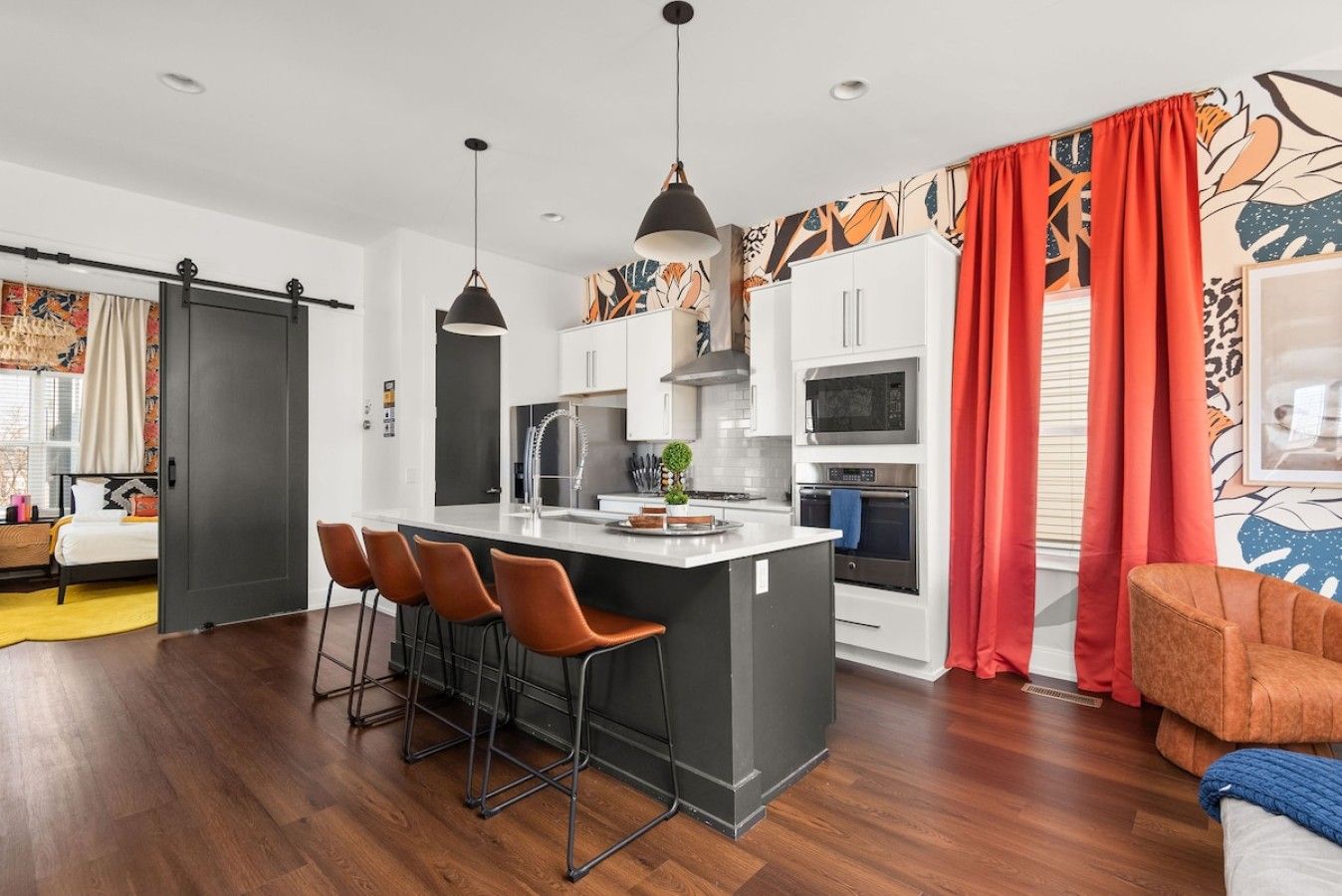 Een moderne keuken met een centraal eiland, barkrukken en een zithoek met een bank.