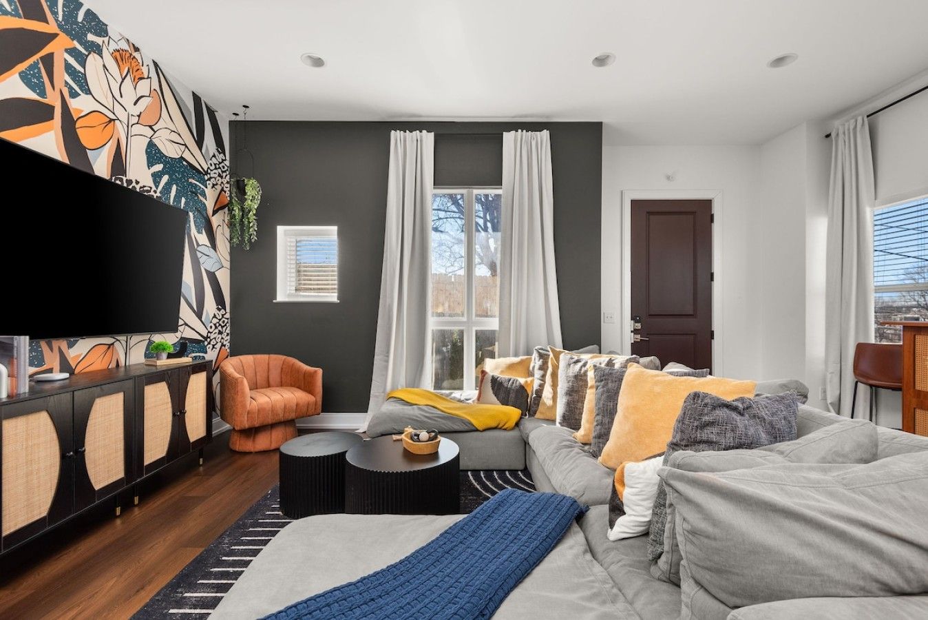 Un salon moderne avec un canapé, un fauteuil et un téléviseur à écran plat.