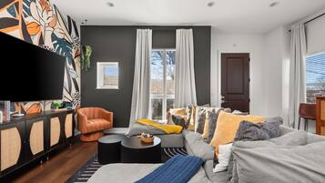 Un salon moderne avec un canapé, un fauteuil et un téléviseur à écran plat.