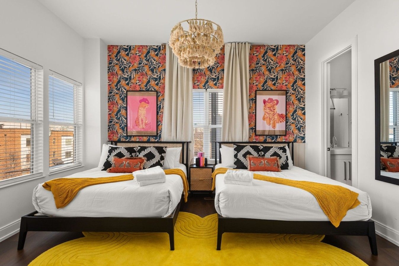A bedroom with two beds, a yellow rug, and a large window.
