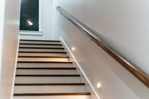 A modern staircase with wooden steps and a metal handrail, leading to a dark interior. - Music City Luxury Walk Out Deck | Spacious 3BR Home (Nashville)