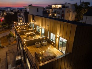 A modern building with a rooftop terrace featuring outdoor seating and string lights. - Music City Luxury Walk Out Deck | Spacious 3BR Home (Nashville)