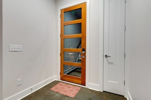 A room with a wooden door, a white wall, and a red patterned rug. - Music City Luxury Walk Out Deck | Spacious 3BR Home (Nashville)