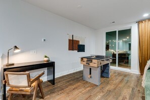 A room with a desk, chair, foosball table, and a view through a glass door. - Stylish Nashville Getaway • Cozy 3BR Near Downtown (Nashville)