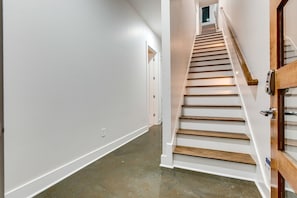 Un pasillo con una escalera de madera que conduce a una puerta.
