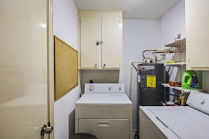 A compact laundry room with a washing machine, dryer, and a water heater. - Driftwood Cove- Close to the beach (Galveston)