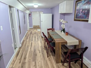 A narrow hallway with a wooden floor leading to a dining area with a table and chairs. - NYC Minutes Away - Afordable Spacious Private Apartment. (West New York)