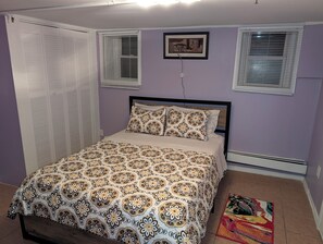 A bedroom with a bed, a wardrobe, two windows with blinds, a wall-mounted picture, and a radiator. - NYC Minutes Away - Afordable Spacious Private Apartment. (West New York)