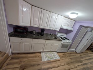 A kitchen with white cabinets, a microwave, a toaster, a coffee maker, a sink, and a stove. - NYC Minutes Away - Afordable Spacious Private Apartment. (West New York)
