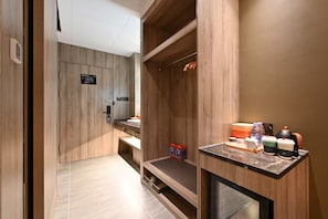 Una habitación de hotel moderna con detalles de madera, un escritorio integrado con cafetera y una pequeña zona de estar.