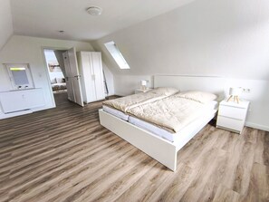 Ein geräumiges Schlafzimmer mit einem großen Bett, einem Kleiderschrank und einem Schreibtisch.