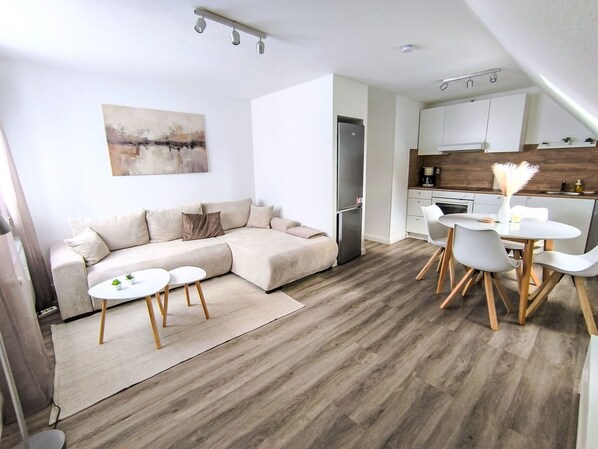 Eine moderne Wohnung mit Wohnbereich, Küchenzeile und Essplatz.
