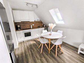 Una cocina moderna con armarios blancos, encimera de madera y horno empotrado.
