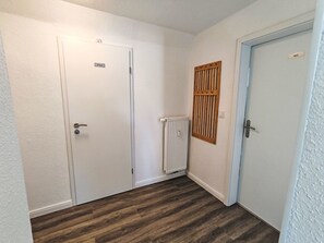 Un pasillo con dos puertas blancas, una con la etiqueta 'Private' y la otra 'WC'. Un radiador está montado en la pared entre las puertas.