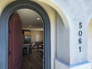 An entrance with a red door, a number '5061' on the wall, and a view into a modern living area with a kitchen and seating. - Rooftop sunsets, central to all of San Diego (San Diego)