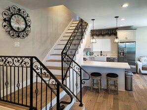 A modern kitchen with a central island, stainless steel appliances, and a staircase with ornate black railings. - Rooftop sunsets, central to all of San Diego (San Diego)
