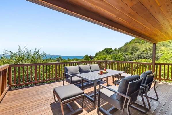 An outdoor deck with a table and chairs, overlooking a scenic landscape.