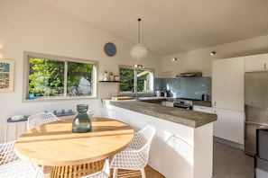 Een moderne keuken met een centraal eiland, witte kasten en een groot raam met uitzicht op groen.
