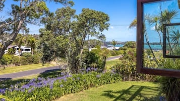 Un jardín exuberante con diversas plantas y flores, un camino y vista a un cuerpo de agua.