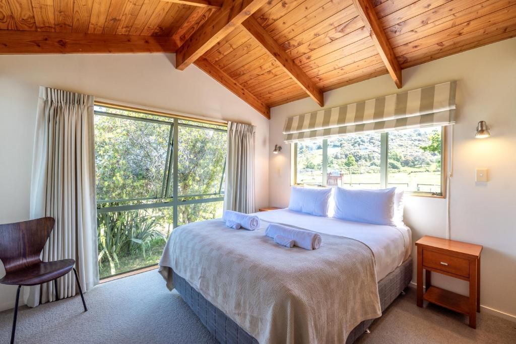 A bedroom with a bed, a chair, a nightstand, and large windows.