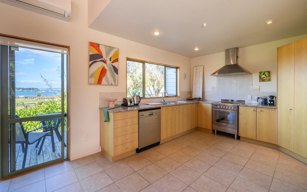 A modern kitchen with a dishwasher, oven, and a large window overlooking a scenic view.