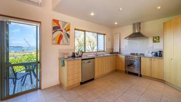 A modern kitchen with a dishwasher, oven, and a large window overlooking a scenic view.