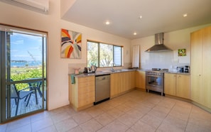 A modern kitchen with a dishwasher, oven, and a large window overlooking a scenic view.