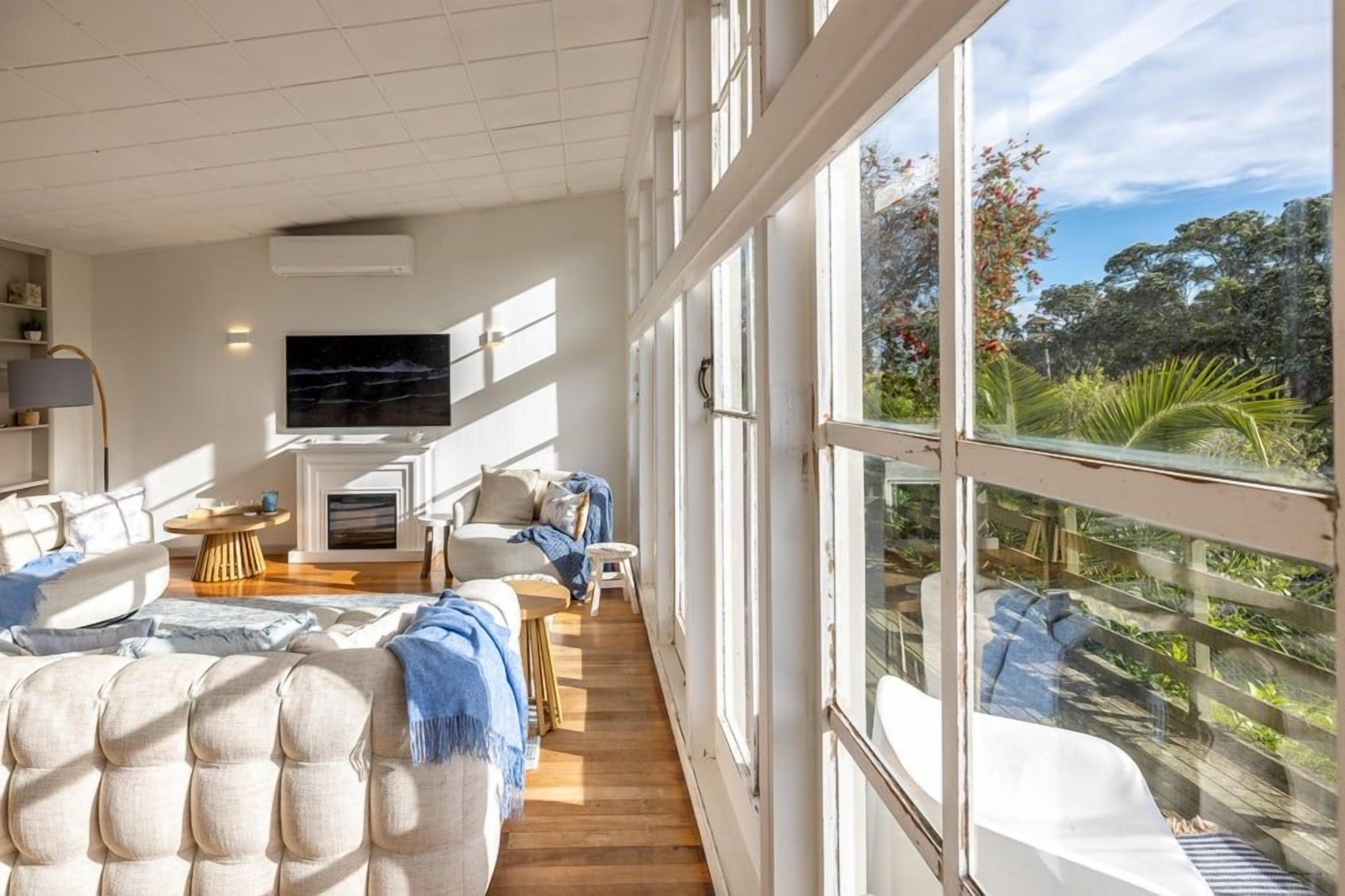 A spacious living room with a large window, a flat-screen TV, and a cozy seating area.